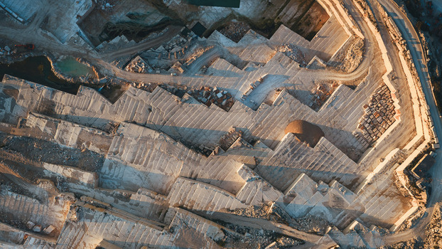 Aerial view of Jadrankamen stone quarry with terraced limestone layers and industrial tracks in warm sunset light in Pucisca Splitsko dalmatinska Croatia. Aerial view of Jadrankamen stone quarry with terraced limestone layers and industrial tracks in warm sunset light in Pucisca Splitsko dalmatinska Croatia.