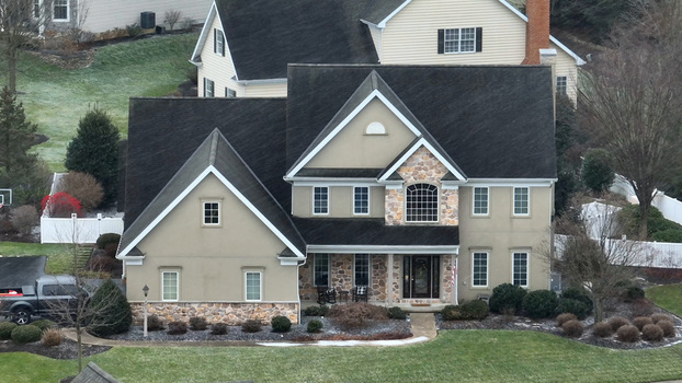 Aerial view of a residential house with stone and stucco facade dark roof and snow covered lawn in Neffsville Pennsylvania United States.