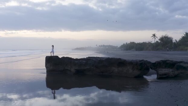 Aerial view of a woman standing on a rock at Pasut Beach Indonesia.