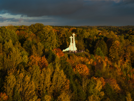 Aerial view of the Three Crosses monument standing proudly atop the hill amidst a tapestry of autumn colors contrasting with the dark sky Vilnius Lithuania. Aerial view of the Three Crosses monument standing proudly atop the hill amidst a tapestry of autumn colors contrasting with the dark sky Vilnius Lithuania.