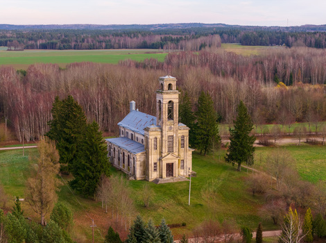 Aerial view of the historic Palendriai church with its tall bell tower surrounded by evergreen trees and a vast forest in Palendriai Siauliu apskritis Lithuania.