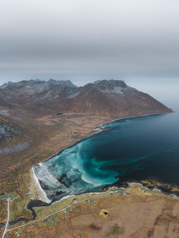 Aerial view of the dramatic coastline of Senja with turquoise waters rugged mountains and autumn colored tundra in Senja Troms Norway.