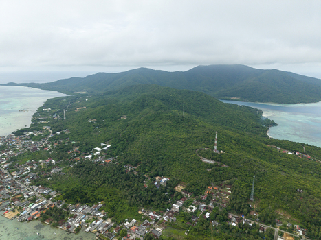 Aerial view of a lush island paradise where emerald forests meet turquoise waters dotted with structures and towers Karimunjawa Central Java Indonesia. Aerial view of a lush island paradise where emerald forests meet turquoise waters dotted with structures and towers Karimunjawa Central Java Indonesia.