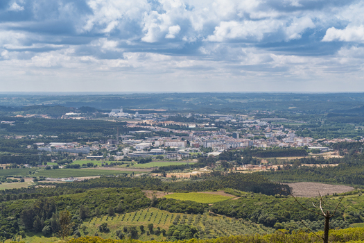View of the town nestled among green hills and wind turbines from the Parque Eolico da Serra dos Candeeiros under a cloudy sky in Rio Maior Santarem Portugal. View of the town nestled among green hills and wind turbines from the Parque Eolico da Serra dos Candeeiros under a cloudy sky in Rio Maior Santarem Portugal.