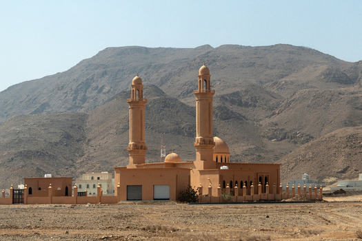 View of a mosque with two minarets and a dome set against arid mountains in the desert landscape of Muscat Muscat Governorate Oman. View of a mosque with two minarets and a dome set against arid mountains in the desert landscape of Muscat Muscat Governorate Oman.