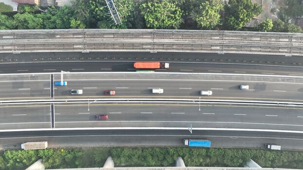 Aerial view of a multi lane highway with cars and trucks driving along the asphalt road in Bekasi Barat West Java Indonesia. Aerial view of a multi lane highway with cars and trucks driving along the asphalt road in Bekasi Barat West Java Indonesia.