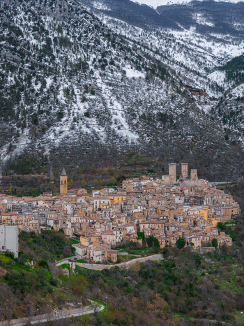 Aerial view of the medieval village featuring historic stone architecture and the Caldora Castle towers under a snow dusted mountain peak Pacentro Abruzzo Italy. Aerial view of the medieval village featuring historic stone architecture and the Caldora Castle towers under a snow dusted mountain peak Pacentro Abruzzo Italy.