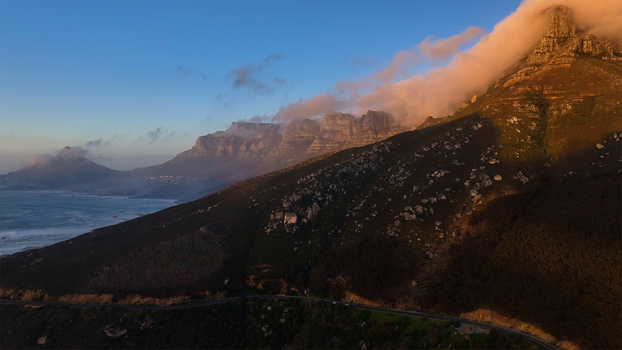 Aerial view of the Twelve Apostles mountain range with clouds rolling over the peaks and the Atlantic Ocean at sunset in Cape Town Western Cape South Africa. Aerial view of the Twelve Apostles mountain range with clouds rolling over the peaks and the Atlantic Ocean at sunset in Cape Town Western Cape South Africa.