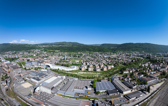 Aerial view of the Swatch and Omega headquarters with its unique curved architecture surrounding industrial complexes and residential districts Biel Bienne Canton of Bern Switzerland.
