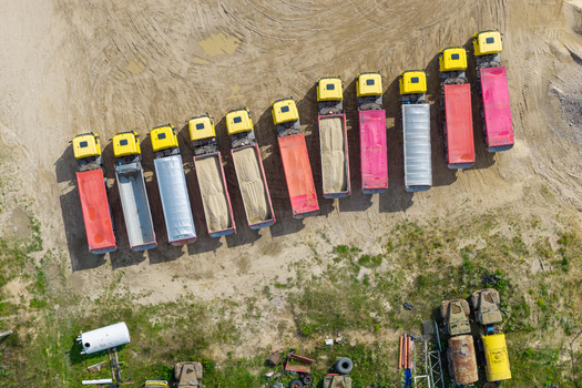 Aerial view of a sand and gravel mine with a row of parked dump trucks loaded with sand and gravel in Masovian Voivodeship Poland.