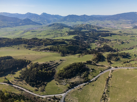 Aerial view of the rolling green hills and dense forests surrounding the village of Valaska Dubova with a winding road under a clear blue sky in Valaska Dubova Zilina Region Slovakia. Aerial view of the rolling green hills and dense forests surrounding the village of Valaska Dubova with a winding road under a clear blue sky in Valaska Dubova Zilina Region Slovakia.