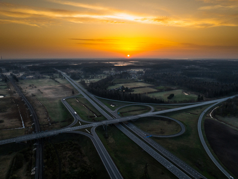 Aerial view of the A5 and A8 highway interchange at sunrise surrounded by rural fields and forests in Olaine parish Olaine Municipality Latvia. Aerial view of the A5 and A8 highway interchange at sunrise surrounded by rural fields and forests in Olaine parish Olaine Municipality Latvia.