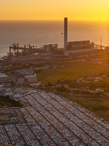 Aerial view of the Centrale Termoelettrica Torrevaldaliga Nord power plant with its tall chimney and a vast car storage lot near the coastline at sunset in Civitavecchia Lazio Italy. Aerial view of the Centrale Termoelettrica Torrevaldaliga Nord power plant with its tall chimney and a vast car storage lot near the coastline at sunset in Civitavecchia Lazio Italy.