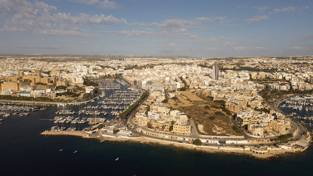 Aerial view of the marina and urban landscape featuring yachts docked in the harbor historic stone buildings and coastal roads under a clear blue sky in Valletta Port Region Malta. Aerial view of the marina and urban landscape featuring yachts docked in the harbor historic stone buildings and coastal roads under a clear blue sky in Valletta Port Region Malta.