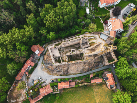 Aerial view of Okor Castle ruins surrounded by lush green forests stone walls and red tiled roofs in the countryside in Okor Central Bohemian Region Czechia. Aerial view of Okor Castle ruins surrounded by lush green forests stone walls and red tiled roofs in the countryside in Okor Central Bohemian Region Czechia.