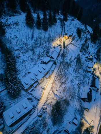 Aerial view of the historic village of Spania Dolina with snow covered roofs and glowing lights nestled among pine trees at dusk Spania Dolina Banska Bystrica Region Slovakia. Aerial view of the historic village of Spania Dolina with snow covered roofs and glowing lights nestled among pine trees at dusk Spania Dolina Banska Bystrica Region Slovakia.