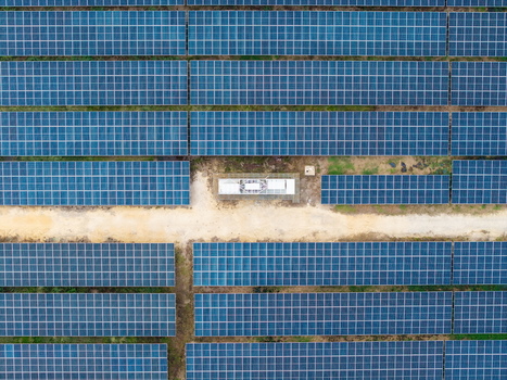 Aerial view of a large scale solar photovoltaic power plant with rows of blue panels and a maintenance structure along a dirt path in Central Seberang Perai Penang Malaysia. Aerial view of a large scale solar photovoltaic power plant with rows of blue panels and a maintenance structure along a dirt path in Central Seberang Perai Penang Malaysia.