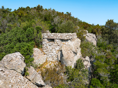 Aerial view of the historic stone bunker at Passo del Monumento integrated into the rocky hillside and dense Mediterranean vegetation Campo nell Elba Toscana Italy.