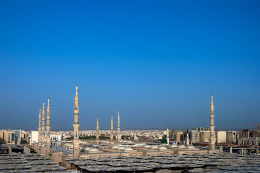 View of Al Masjid e Nabawi with its iconic minarets and expansive courtyard under a clear blue sky in Madinah Al Madinah Province Saudi Arabia. View of Al Masjid e Nabawi with its iconic minarets and expansive courtyard under a clear blue sky in Madinah Al Madinah Province Saudi Arabia.