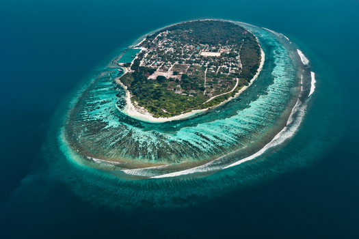 Aerial view of a lush tropical island with dense palm forests white sandy beaches and a vibrant coral reef in Vaikaradhoo Haa Dhaalu Atoll Maldives. Aerial view of a lush tropical island with dense palm forests white sandy beaches and a vibrant coral reef in Vaikaradhoo Haa Dhaalu Atoll Maldives.