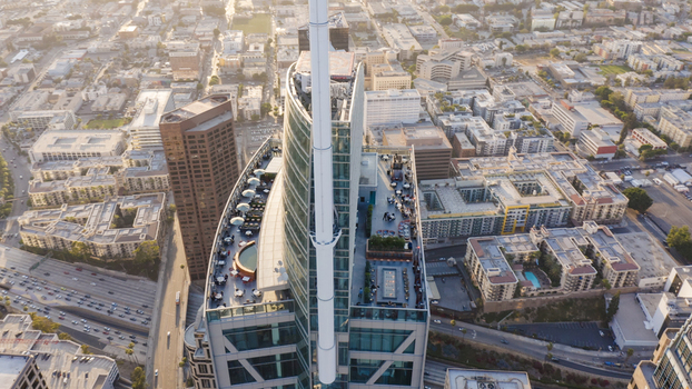 Aerial view of the Wilshire Grand Center featuring a rooftop terrace with outdoor seating surrounded by the dense urban skyline and city streets in Los Angeles California United States.