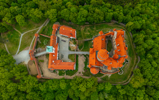 Aerial view of Bouzov Castle with its distinctive red tiled roofs and historic courtyards nestled within a lush green forest in Bouzov Olomoucky kraj Czechia. Aerial view of Bouzov Castle with its distinctive red tiled roofs and historic courtyards nestled within a lush green forest in Bouzov Olomoucky kraj Czechia.
