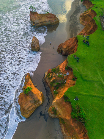 Aerial view of the dramatic coastline of Bali featuring rugged cliffs lush green grass and sea stacks rising from the ocean in Bali Indonesia. Aerial view of the dramatic coastline of Bali featuring rugged cliffs lush green grass and sea stacks rising from the ocean in Bali Indonesia.