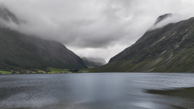 Aerial view of a serene lake nestled between towering mountains under a dramatic cloudy sky in Nordland Norway. Aerial view of a serene lake nestled between towering mountains under a dramatic cloudy sky in Nordland Norway.