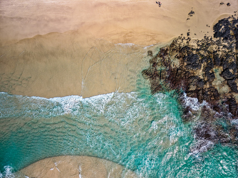 Aerial view of Cudgen Headland South Head featuring turquoise ocean waves crashing against dark volcanic rocks and golden sand in Kingscliff New South Wales Australia. Aerial view of Cudgen Headland South Head featuring turquoise ocean waves crashing against dark volcanic rocks and golden sand in Kingscliff New South Wales Australia.