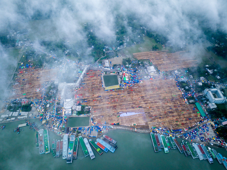 Aerial view of a bustling waterfront market where colorful boats line the shore against a backdrop of earthy stalls and verdant fields Charmonai Barisal Division Bangladesh. Aerial view of a bustling waterfront market where colorful boats line the shore against a backdrop of earthy stalls and verdant fields Charmonai Barisal Division Bangladesh.