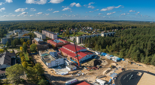Aerial view of a construction site featuring a red roofed building a crane and surrounding forest in Latvia. Aerial view of a construction site featuring a red roofed building a crane and surrounding forest in Latvia.