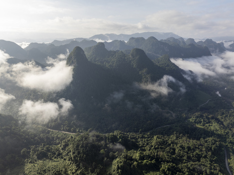 Aerial view of the karst mountain landscape and lush forests of Phong Nha Ke Bang National Park under a misty morning sky in Quang Binh Province Vietnam. Aerial view of the karst mountain landscape and lush forests of Phong Nha Ke Bang National Park under a misty morning sky in Quang Binh Province Vietnam.