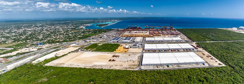 Aerial view of the DP World Dominicana port facility featuring shipping containers industrial warehouses cranes and coastal infrastructure in Boca Chica Santo Domingo Dominican Republic. Aerial view of the DP World Dominicana port facility featuring shipping containers industrial warehouses cranes and coastal infrastructure in Boca Chica Santo Domingo Dominican Republic.