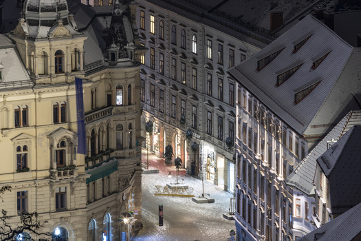View of ornate buildings adorned with snow glowing warmly under the night sky creating a picturesque winter scene in Graz Styria Austria. View of ornate buildings adorned with snow glowing warmly under the night sky creating a picturesque winter scene in Graz Styria Austria.