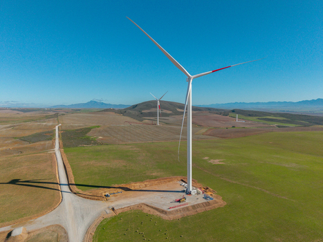 Aerial view of large wind turbines standing in green fields under a clear blue sky Swellendam Western Cape South Africa. Aerial view of large wind turbines standing in green fields under a clear blue sky Swellendam Western Cape South Africa.