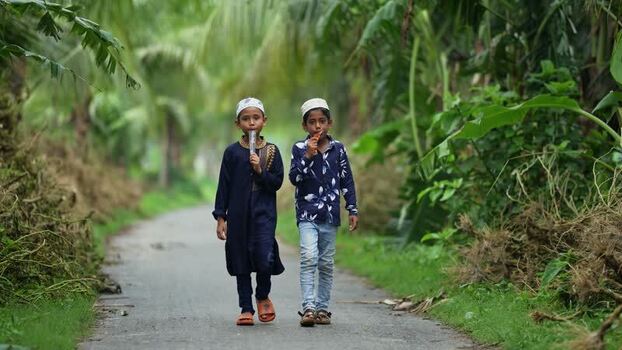 View of two young boys walking and eating snacks in Bogura Bangladesh. View of two young boys walking and eating snacks in Bogura Bangladesh.