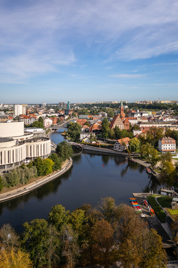 Aerial view of the dark winding river flowing past the Pomeranian Philharmonic and vibrant rooftops with the cathedral spire piercing the skyline Bydgoszcz Województwo kujawsko pomorskie Poland. Aerial view of the dark winding river flowing past the Pomeranian Philharmonic and vibrant rooftops with the cathedral spire piercing the skyline Bydgoszcz Województwo kujawsko pomorskie Poland.
