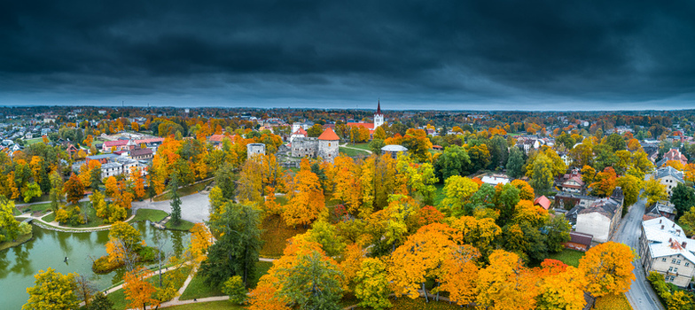 Aerial view of Cesis Castle ruins surrounded by vibrant autumn foliage historic stone walls and lush parkland under a dramatic overcast sky in Cesis Cesis Municipality Latvia. Aerial view of Cesis Castle ruins surrounded by vibrant autumn foliage historic stone walls and lush parkland under a dramatic overcast sky in Cesis Cesis Municipality Latvia.