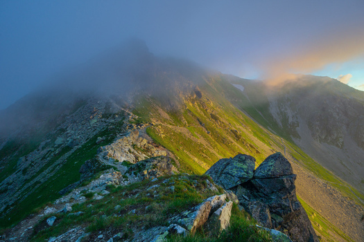 View of Smutne sedlo in Western Tatras with rocky ridges and green slopes under a misty sky at sunset in Ziar Zilina Region Slovakia. View of Smutne sedlo in Western Tatras with rocky ridges and green slopes under a misty sky at sunset in Ziar Zilina Region Slovakia.