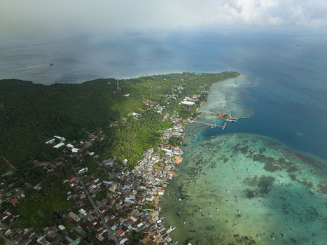 Aerial view of the vibrant coastal settlement meeting the turquoise waters lush green forests and distant horizon Karimunjawa Central Java Indonesia. Aerial view of the vibrant coastal settlement meeting the turquoise waters lush green forests and distant horizon Karimunjawa Central Java Indonesia.