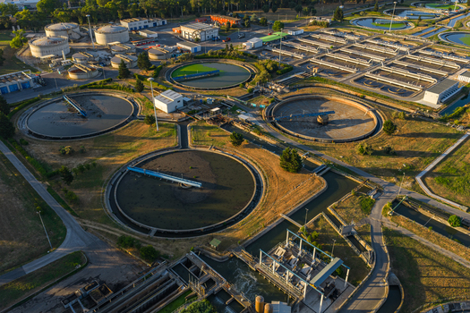 Aerial view of the water treatment plant featuring circular sedimentation tanks concrete infrastructure and surrounding green fields in Rome Lazio Italy.