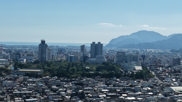 Aerial view of the cityscape of Shizuoka featuring dense urban architecture lush green parks and the distant mountains overlooking Suruga Bay under a clear blue sky Shizuoka Shizuoka Japan. Aerial view of the cityscape of Shizuoka featuring dense urban architecture lush green parks and the distant mountains overlooking Suruga Bay under a clear blue sky Shizuoka Shizuoka Japan.