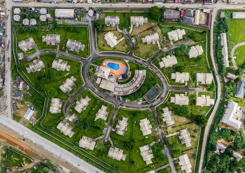Port Harcourt Rivers Nigeria 03 July 2026 Aerial view of a residential estate featuring uniform houses arranged in a circular layout a central swimming pool a tennis court and lush green lawns. Port Harcourt Rivers Nigeria 03 July 2026 Aerial view of a residential estate featuring uniform houses arranged in a circular layout a central swimming pool a tennis court and lush green lawns.