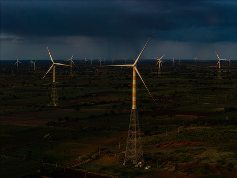 Aerial view of wind turbines standing in a vast rural landscape under a dramatic dark stormy sky in Hampi Karnataka India.