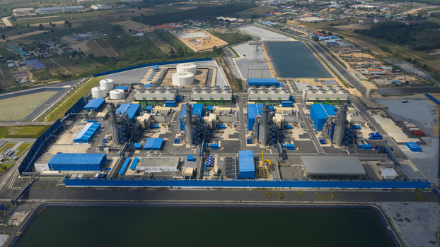 Aerial view of the Gulf Pluak Daeng Power Plant complex with its industrial buildings cooling towers and storage tanks under a clear sky in Map Yang Phon Rayong Thailand.