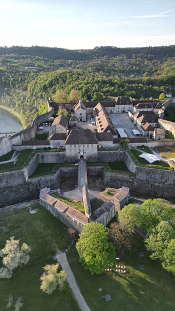 Aerial view of the historic Besancon Citadel with its massive stone walls and ancient buildings overlooking lush green hills in Besancon Bourgogne Franche Comte France. Aerial view of the historic Besancon Citadel with its massive stone walls and ancient buildings overlooking lush green hills in Besancon Bourgogne Franche Comte France.