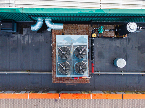 Aerial view of an industrial rooftop featuring a large HVAC cooling unit with four fans metal pipes and ventilation ducts in Riga Latvia. Aerial view of an industrial rooftop featuring a large HVAC cooling unit with four fans metal pipes and ventilation ducts in Riga Latvia.