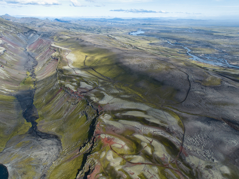 Aerial view of Eldgja volcanic canyon featuring moss covered lava fields rugged terrain and a winding river in the distance in Kirkjubaejarklaustur Skaftarhreppur Iceland. Aerial view of Eldgja volcanic canyon featuring moss covered lava fields rugged terrain and a winding river in the distance in Kirkjubaejarklaustur Skaftarhreppur Iceland.