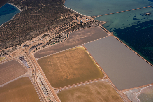 Aerial view of salt evaporation ponds with varying water colors and textures situated along the coastline in Australia. Aerial view of salt evaporation ponds with varying water colors and textures situated along the coastline in Australia.