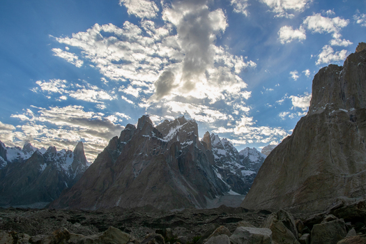 View of Trango Towers in the Karakoram mountain range with jagged granite peaks snow capped summits and dramatic clouds under a bright sky in Pakistan. View of Trango Towers in the Karakoram mountain range with jagged granite peaks snow capped summits and dramatic clouds under a bright sky in Pakistan.